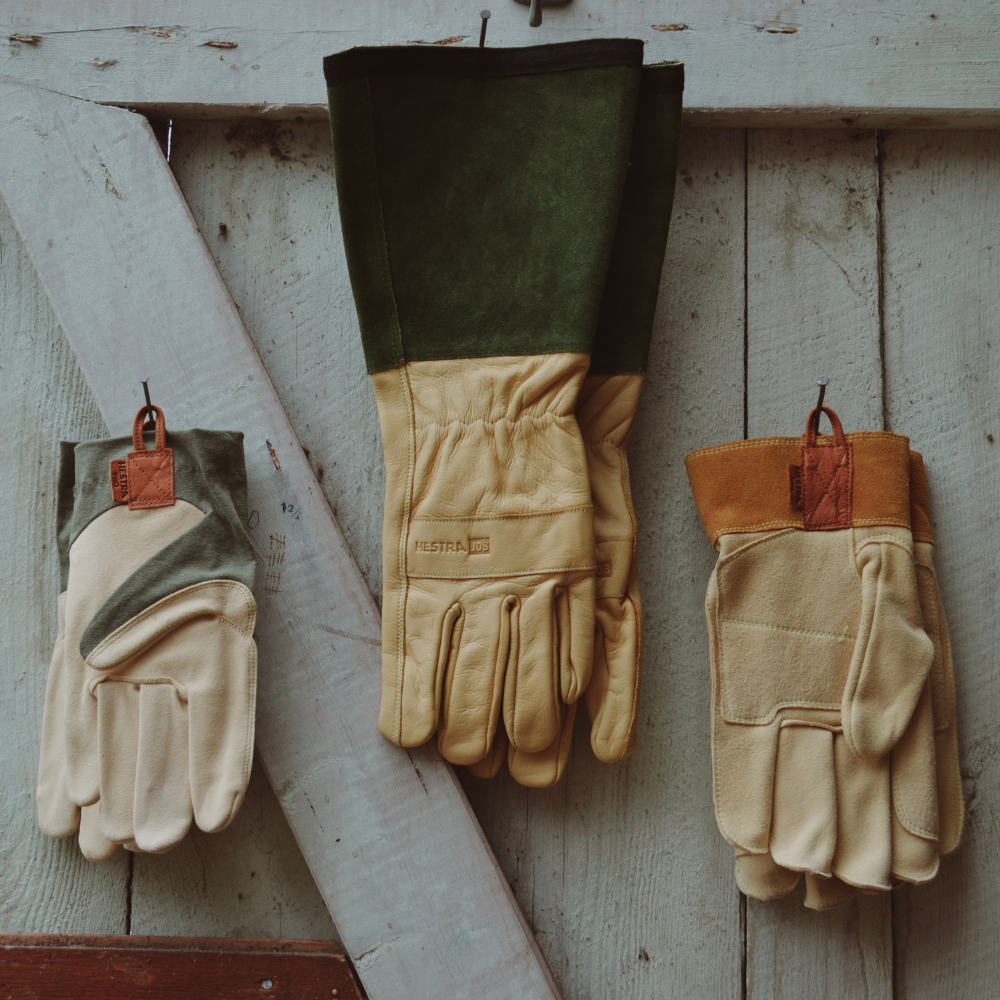 Arbetshandskar upphängda på trävägg i verkstadsmiljö