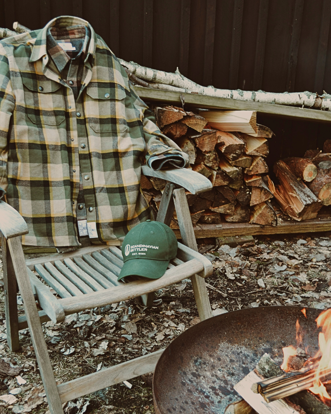 Flanell-overshirt i gröna och bruna toner hängd över en Adirondack-stol utomhus